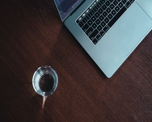 Glass of water on a work desk, highlighting hydration